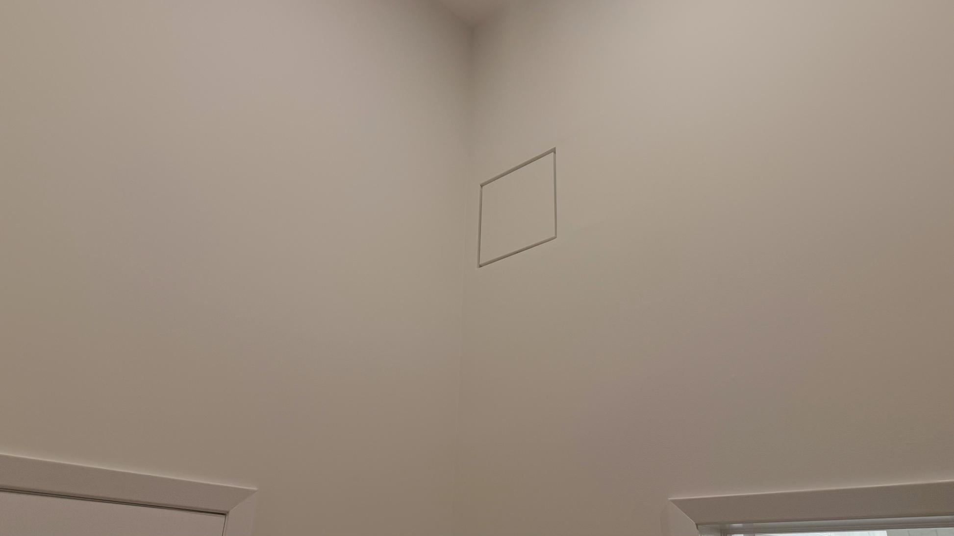 Seam flush wall vent installed flush in a white-on-white wall — sitting perfectly flat against the drywall with no protruding frame, visually disappearing into the wall surface