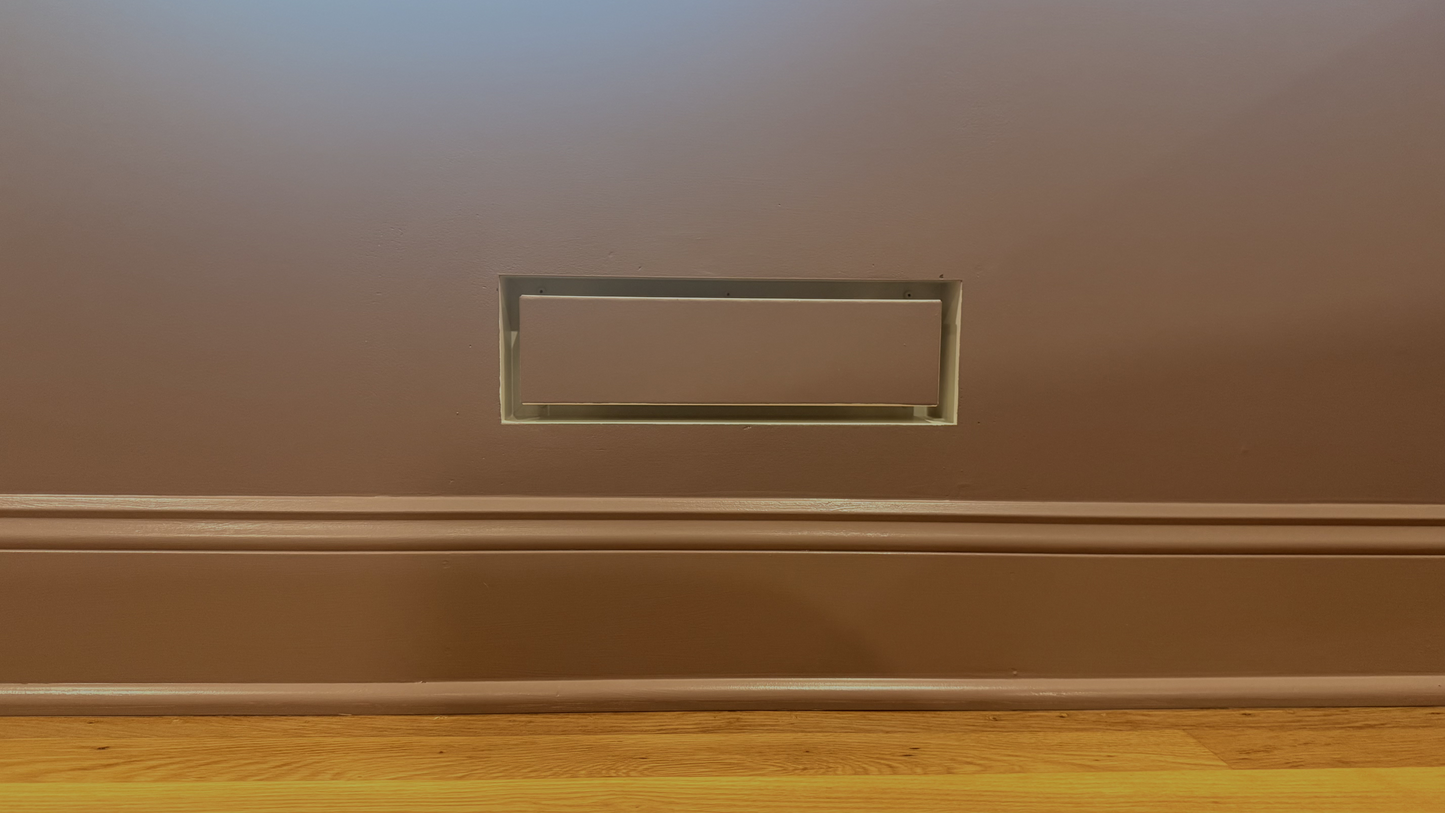 Seam flush wall vent installed and painted to match a deep navy wall — demonstrating the paintable matte powder-coat finish integrating with a dark, saturated wall color