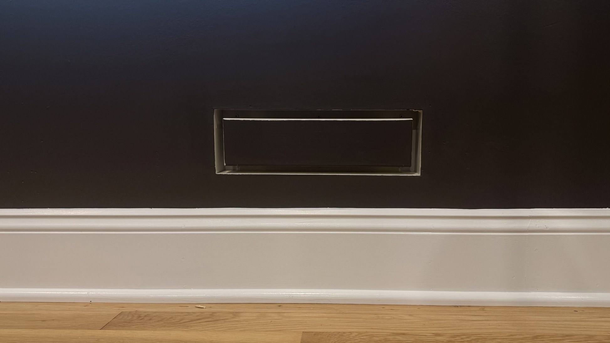 Seam flush wall vent installed and painted to match a warm mauve wall and baseboard — demonstrating the paintable matte powder-coat finish integrating with a muted, warm color palette